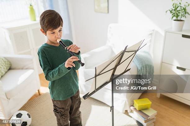 hispanic boy practicing recorder in living room - leggio-per-spartiti-musicali foto e immagini stock