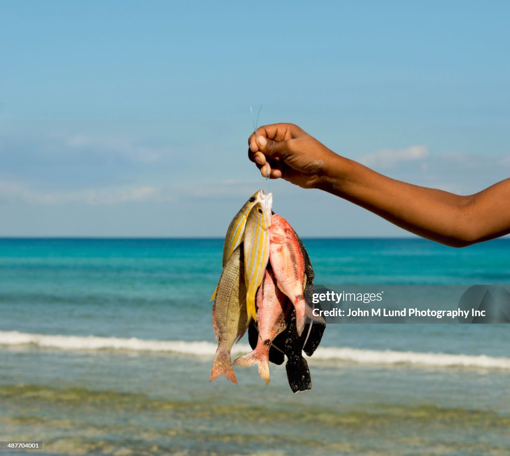 Middle Eastern fisherman holding catch on beach