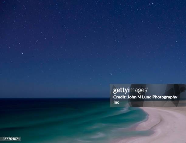 surf washing up on beach under starry sky - beach night stockfoto's en -beelden