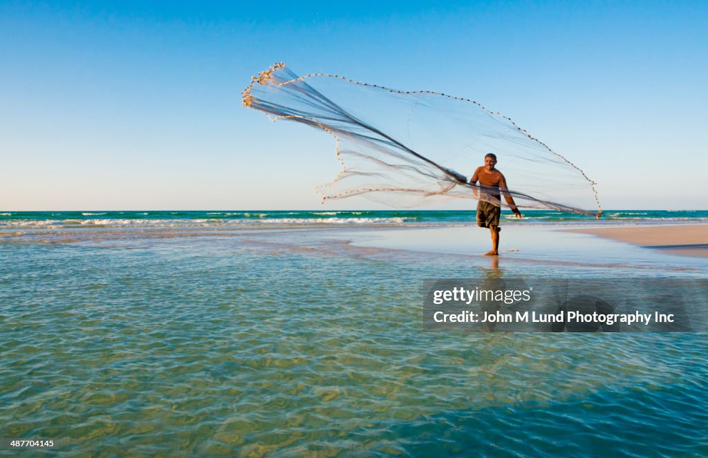 Middle Eastern fisherman casting net on tropical beach