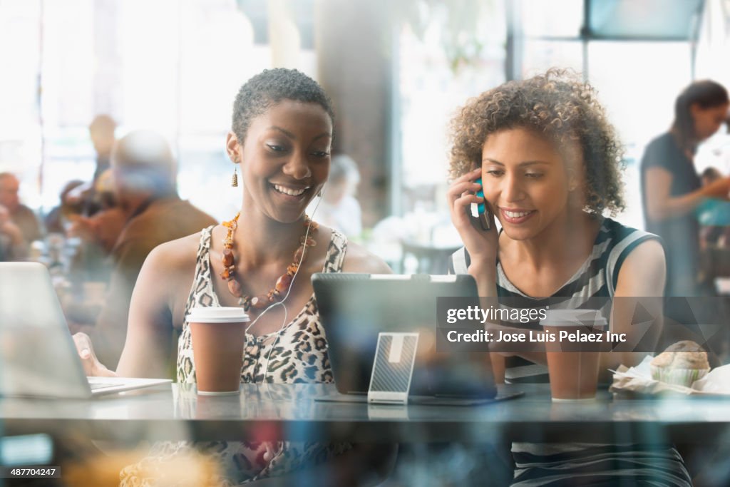 Women using digital tablet in cafe