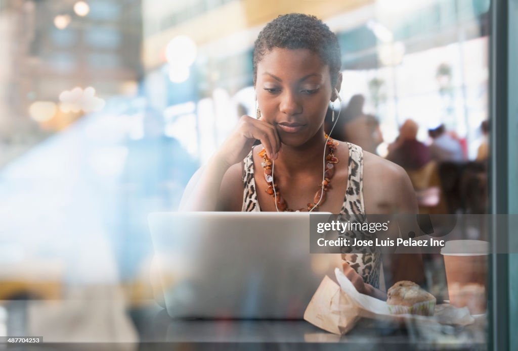 African American woman using laptop in cafe