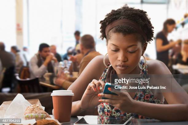 black woman using cell phone in cafe - new orleans people stock pictures, royalty-free photos & images