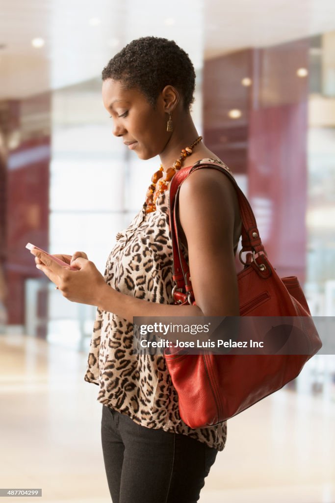 African American woman using cell phone in shopping mall