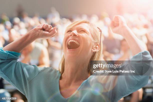 caucasian woman cheering at sporting event - blonde cheering stock-fotos und bilder