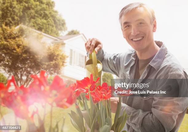 chinese man watering flowers in garden - west new york nueva jersey fotografías e imágenes de stock
