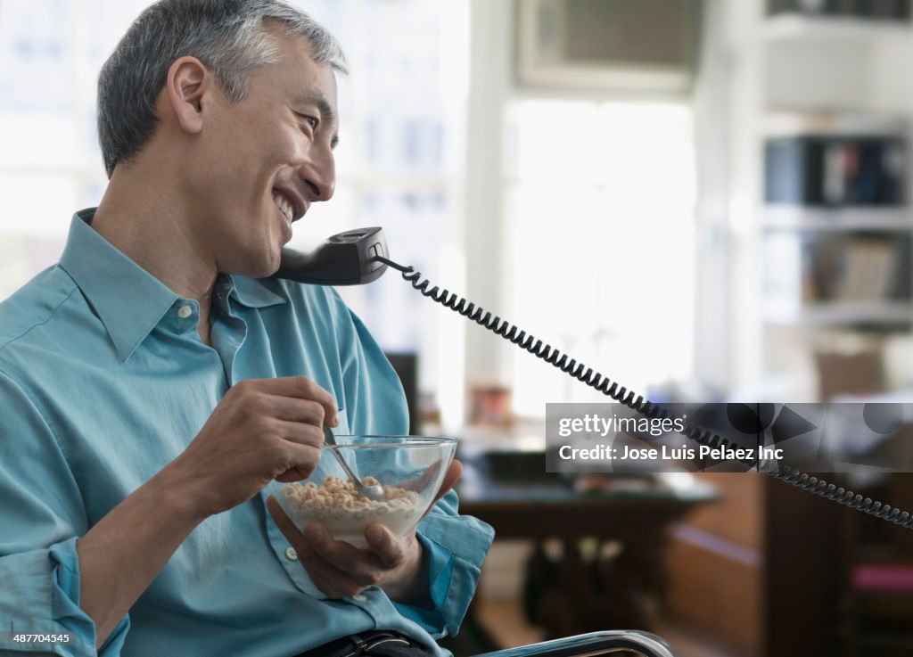 Chinese businessman eating and talking on telephone