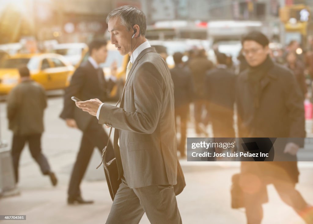 Chinese businessman using cell phone on city street