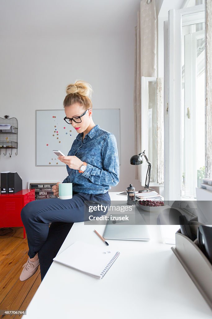 Woman texting on smart phone in an office