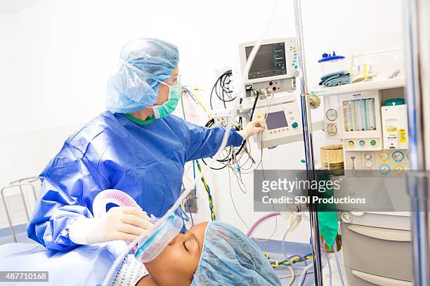 anesthesiologist checking monitors while sedating patient for surgery in hospital - anesthesia stock pictures, royalty-free photos & images