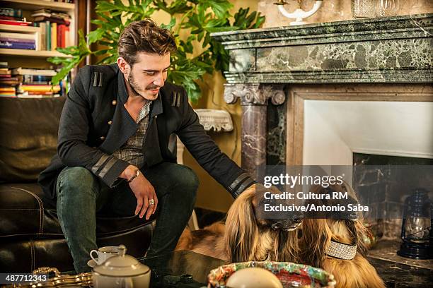 man patting dog by fireplace - afghan ethnicity imagens e fotografias de stock