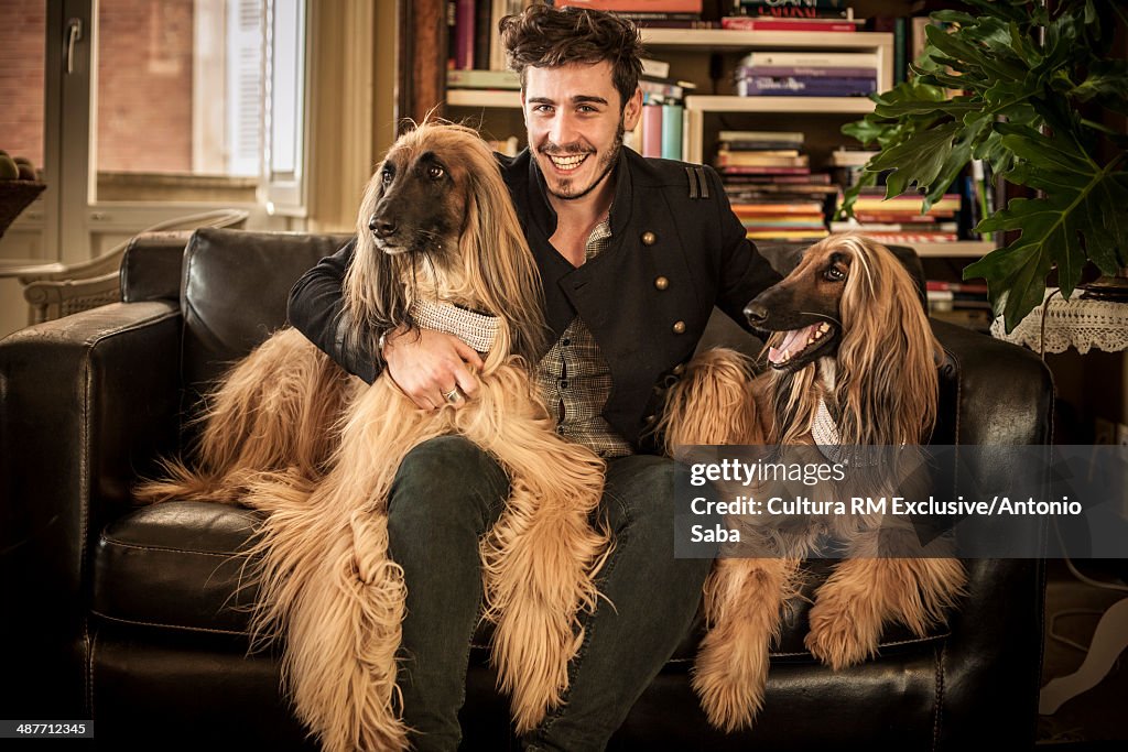 Man flanked by dogs on sofa