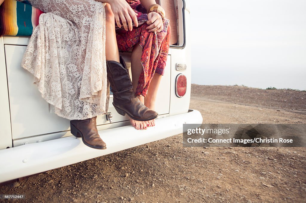 Cropped shot of two women sitting on camper van