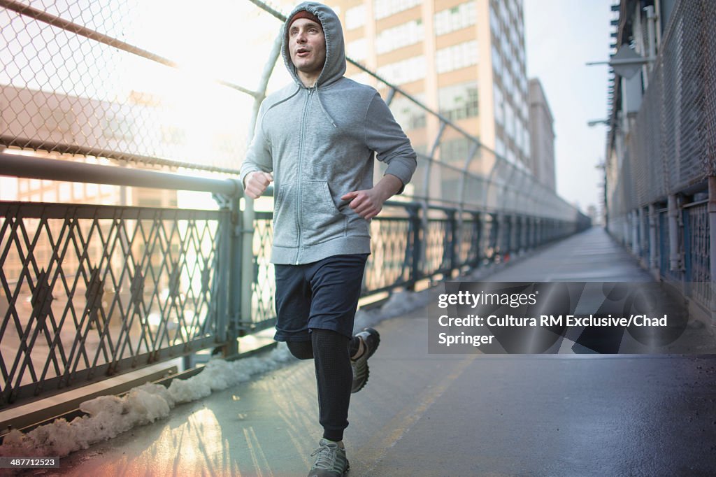 Mid adult man running across bridge