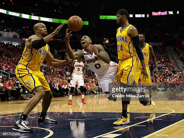 Guard Jeff Teague of the Atlanta Hawks is fouled by forward Paul Geroge of the Indiana Pacers while Pacers forward David West looks on in Game 6 of...