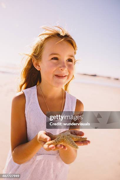 girl holding starfish in hands - starfish holding hands stock pictures, royalty-free photos & images