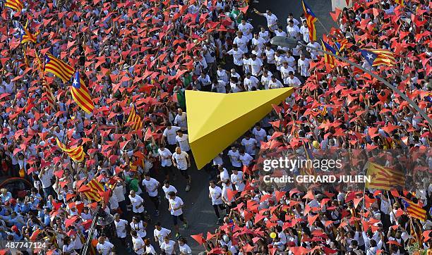 Demonstrators hold a giant yellow cursor on Meridiana street as others wave "Esteladas" flags during celebrations of Catalonia's National Day which...
