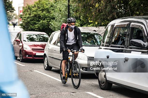 ciclista commuter usando una máscara de contaminación en el centro de londres - contaminación del aire fotografías e imágenes de stock
