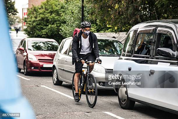 cyclist commuter wearing a pollution-mask in central london - uk city stockfoto's en -beelden
