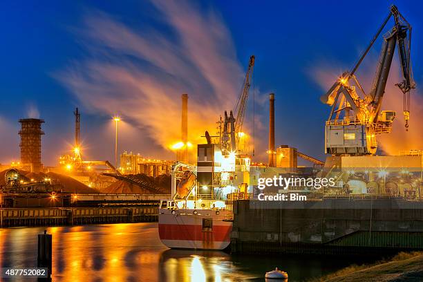 illuminated industrial plant on the river at night, amsterdam, netherlands - industrial district stock pictures, royalty-free photos & images