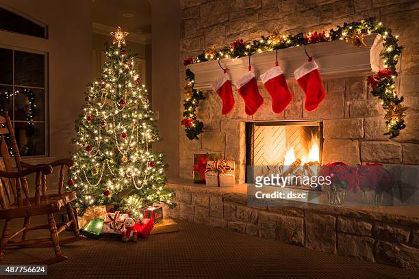 christmas. glowing fireplace, hearth, tree. red stockings. gifts and decorations. - christmas stock pictures, royalty-free photos & images