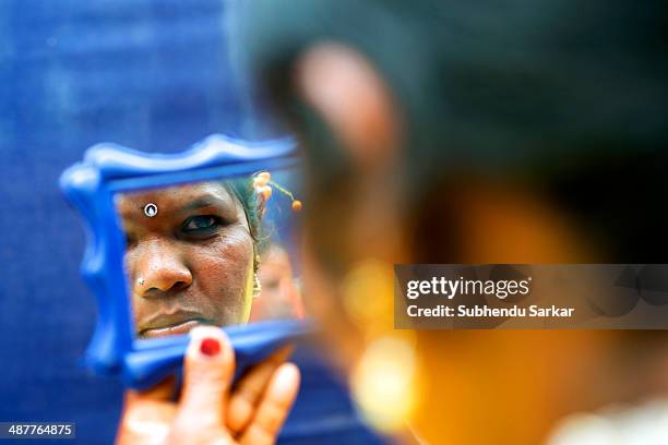 Santhali looks into a mirror after applying make-up during a festive celebration. The Santhal are the largest tribal community in India. They have a...