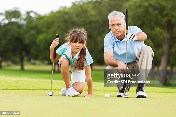 golf instructor teaching technique to little girl - golf clubhouse stockfoto's en -beelden