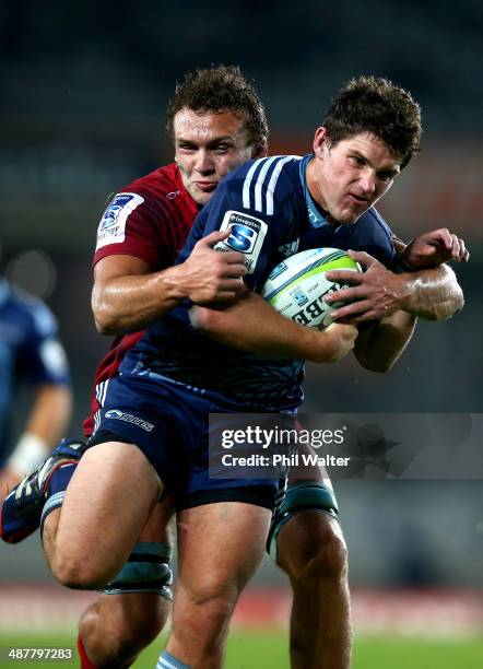 Simon Hickey of the Blues is tackled by Jake Schatz of the Reds during the round 12 Super Rugby match between the Blues and the Reds at Eden Park on...