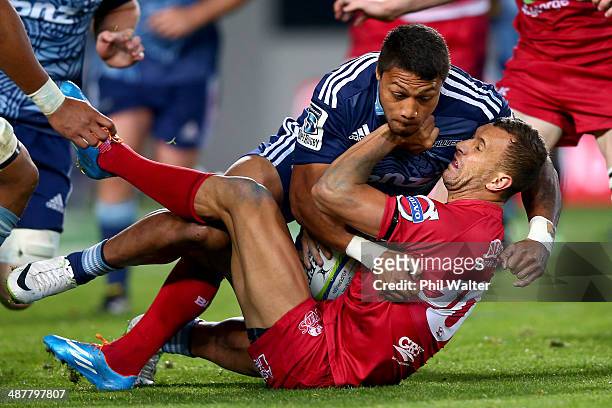 Quade Cooper of the Reds is tackled by George Moala of the Blues during the round 12 Super Rugby match between the Blues and the Reds at Eden Park on...
