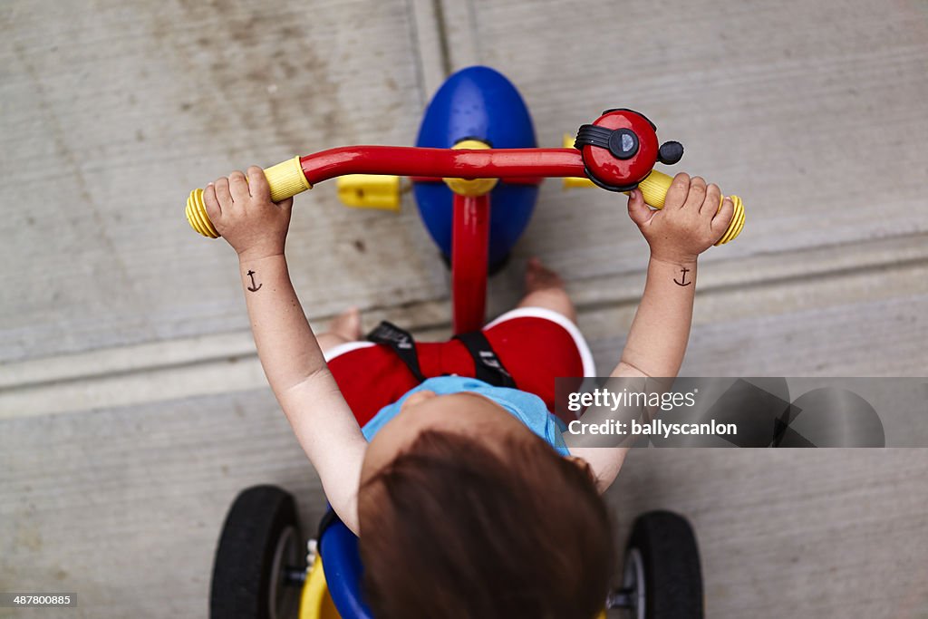 Boy with fake tattoos on tricycle