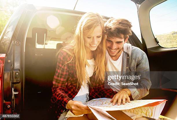 couple looking the itnerary on a map - couple in car smiling stockfoto's en -beelden