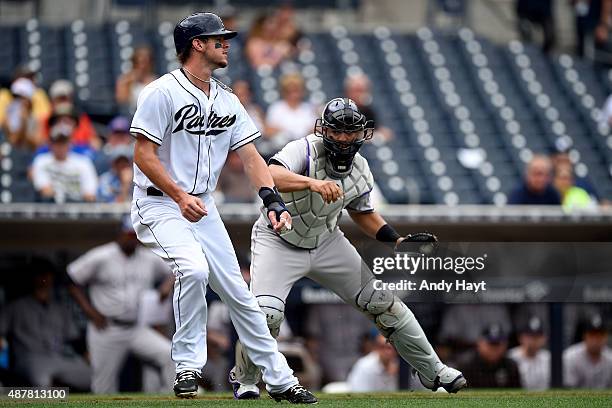Wil Myers of the San Diego Padres gets caught in a run down before being tagged out at home by Wilin Rosario of the Colorado Rockies during the game...