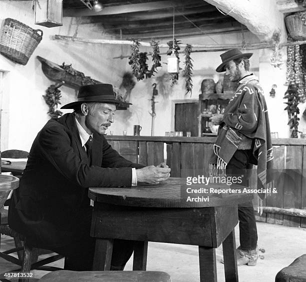 American actor Lee Van Cleef with American actor Clint Eastwood in the movie For a Few Dollars More, directed by Sergio Leone. The former is sitting...
