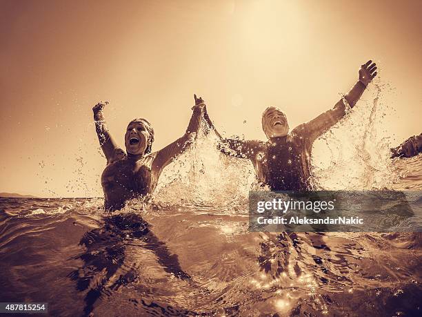 aktive senioren baden im meer - old couple jumping stock-fotos und bilder