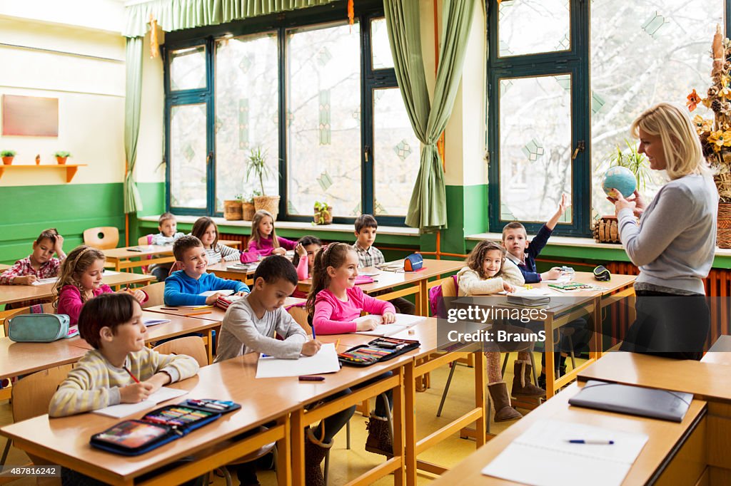 Female teacher teaching geography to group of elementary students.