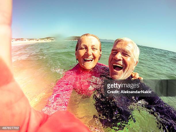 vacation selfie of a senior couple - older couple hugging on beach stock pictures, royalty-free photos & images