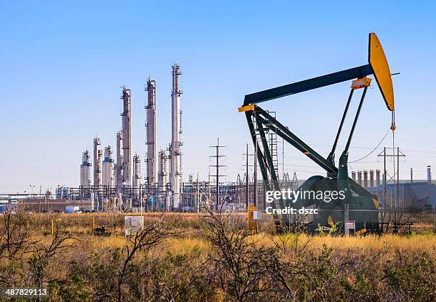 pumpjack (oil derrick) and refinery plant in west texas - olieraffinaderij stockfoto's en -beelden