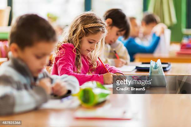 group of school children sitting in the classroom and writing. - elementary school building stock pictures, royalty-free photos & images