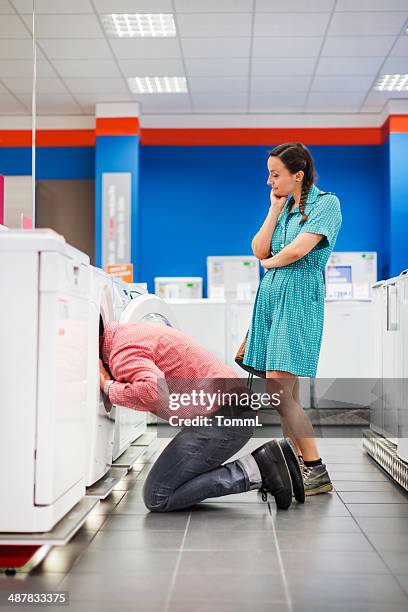 young couple checking whiteware in appliance store - funny fridge stock pictures, royalty-free photos & images