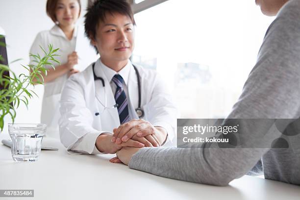 doctor holding patient's hand - puke japan stock pictures, royalty-free photos & images