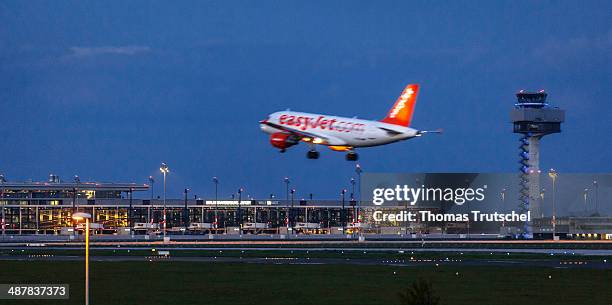 Aircraft of easyet arrives at Berlin Schoenefeld Airport at night, in the back one can see the terminal and tower of Berlin Brandenburg airport on...