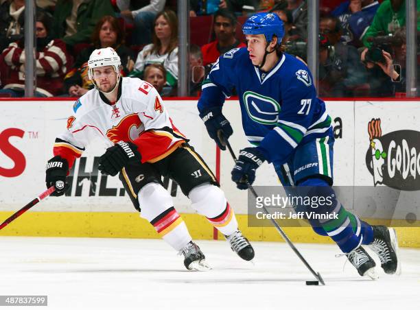 Kris Russell of the Calgary Flames and Shawn Matthias of the Vancouver Canucks skate up ice during their NHL game at Rogers Arena April 13, 2014 in...