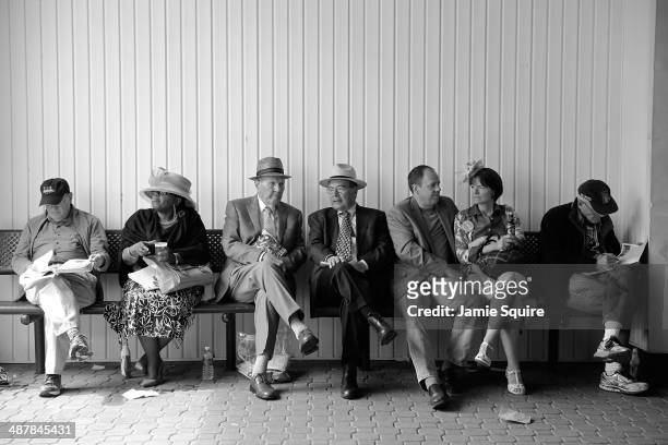 Race fans sit while wearing festive hats prior to the 140th running of the Kentucky Oaks at Churchill Downs on May 2, 2014 in Louisville, Kentucky.