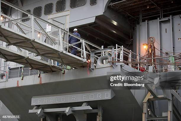 Shipbuilder walks onto the USS Gerald R. Ford aircraft carrier during outfitting and testing at Huntington Ingalls Industries' Newport News...