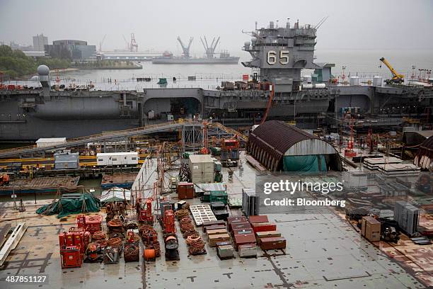 Equipment sits on the deck of the USS Gerald R. Ford aircraft carrier during outfitting and testing as the USS Enterprise floats pier side during...