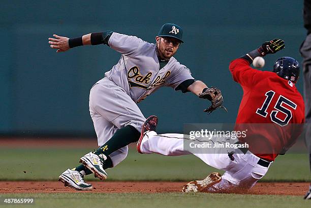 Dustin Pedroia of the Boston Red Sox slides in to second as Eric Sogard of the Oakland Athletics fields an errant throw in the first inning at Fenway...