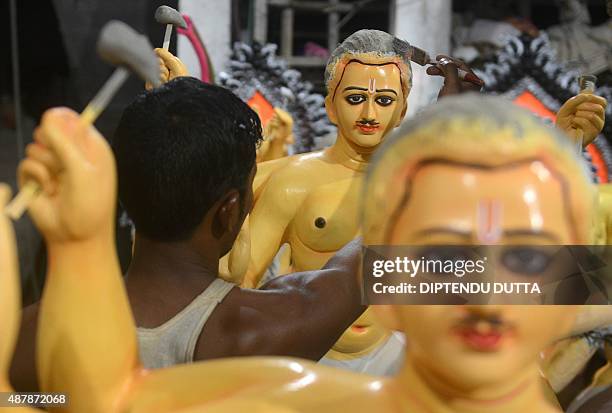 An Indian artist works on an idol of the Hindu god Biswakarma at the artisan village, known locally as Kumartoli, in Siliguri on September 12, 2015....