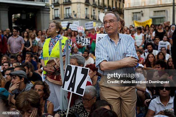 Protesters listen a speech as a placard reads 'Peace' during a demonstration to show solidarity and support for refugees on September 12, 2015 in...