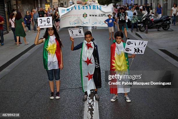 Children pose for pictures as they wear Syrian Independent flag and Kurdistan flag while holding placards reading 'Assad equal to DAESH' during a...