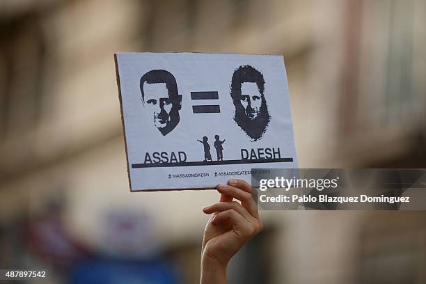 Holds a placard reading 'Assad equal to DAESH' during a demonstration to show solidarity and support for refugees on September 12, 2015 in Madrid,...